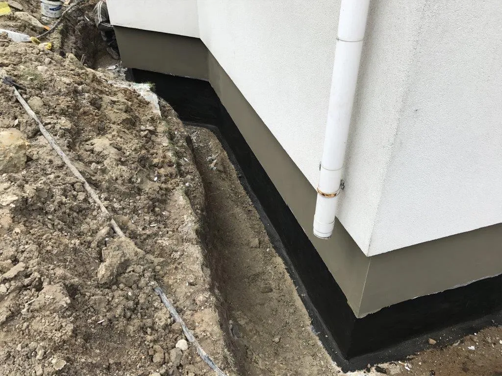 Czarna powłoka bitumiczna na ścianie fundamentowej budynku